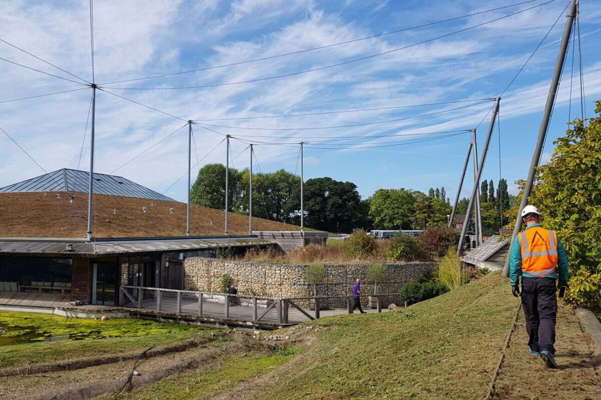 Technicians securing support cables for tensile roof system